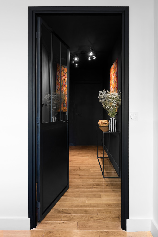 Inspiration för en liten skandinavisk hall, med svarta väggar, mellanmörkt trägolv, en enkeldörr och en svart dörr