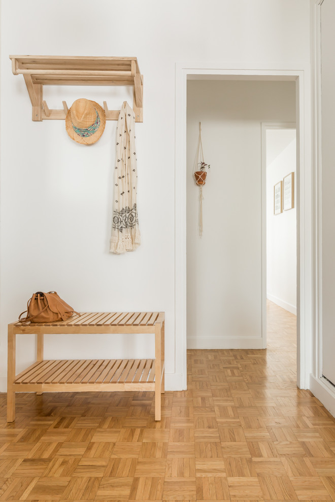Diseño de distribuidor nórdico con paredes blancas, suelo de madera clara, suelo marrón y puerta blanca