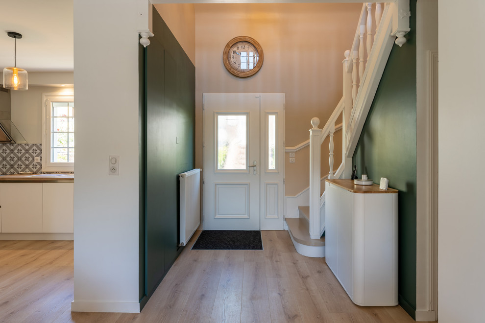 Minimalistisk inredning av en stor foajé, med gröna väggar, ljust trägolv, en enkeldörr och en vit dörr