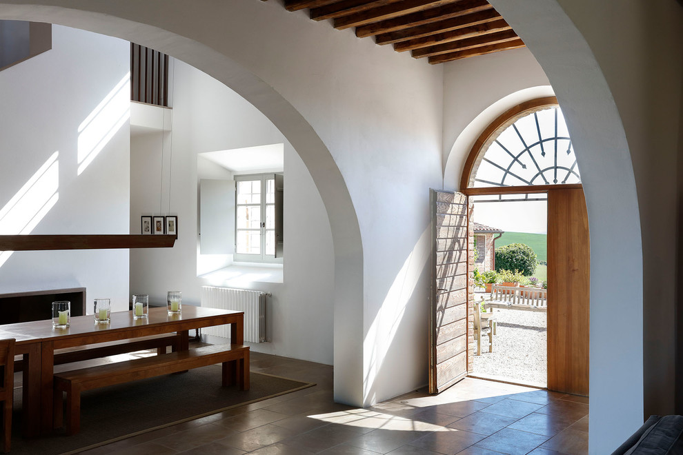 Cette image montre une porte d'entrée minimaliste avec un mur blanc, une porte double, une porte en bois brun et un sol marron.