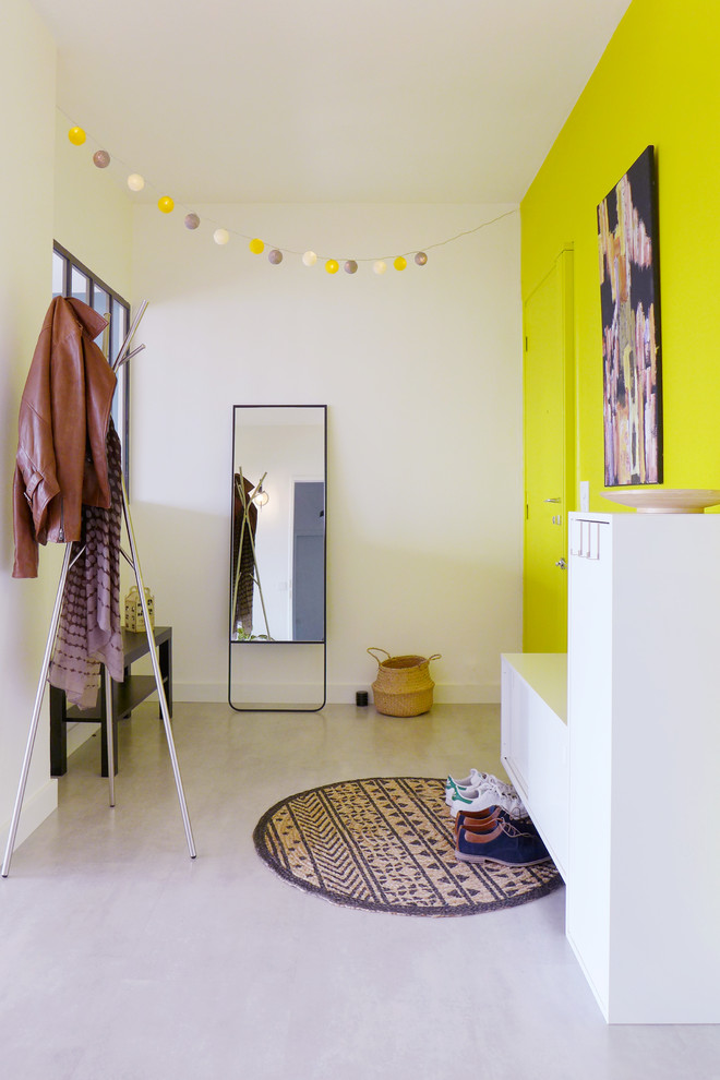 Inspiration för stora moderna foajéer, med gula väggar, betonggolv, en enkeldörr, en gul dörr och grått golv