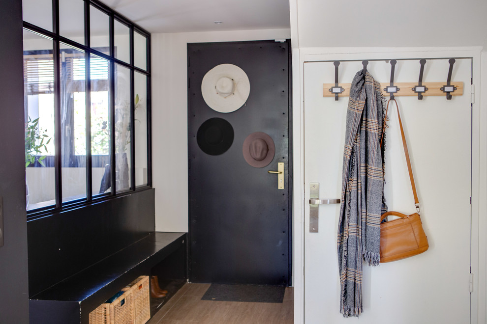 Стильный дизайн: узкая прихожая среднего размера в современном стиле с белыми стенами, одностворчатой входной дверью, черной входной дверью, коричневым полом и полом из керамической плитки - последний тренд