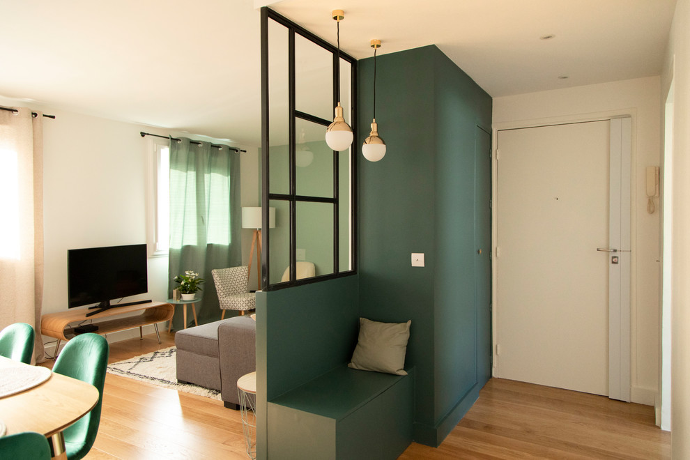 Idée de décoration pour un petit hall d'entrée minimaliste avec un mur vert, un sol en bois brun, une porte simple, une porte blanche et un sol marron.