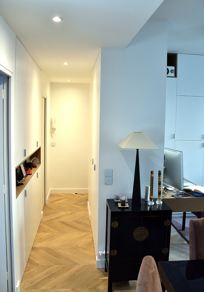 Kleiner Moderner Eingang mit Korridor, weißer Wandfarbe, hellem Holzboden, Einzeltür und weißer Haustür in Paris