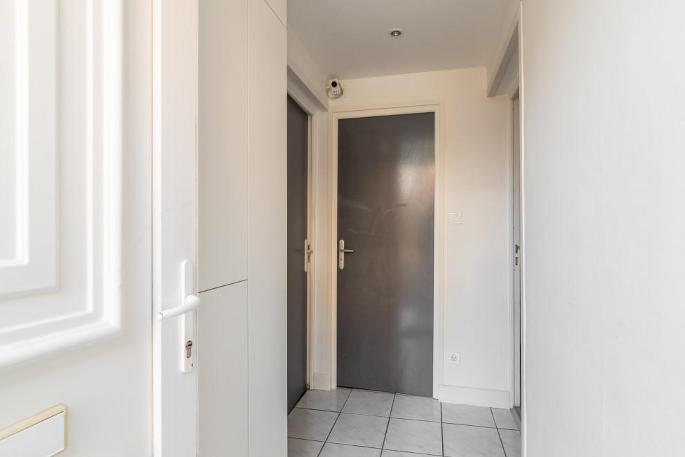 На фото: фойе среднего размера в стиле модернизм с белыми стенами, полом из терракотовой плитки, одностворчатой входной дверью, белой входной дверью и белым полом