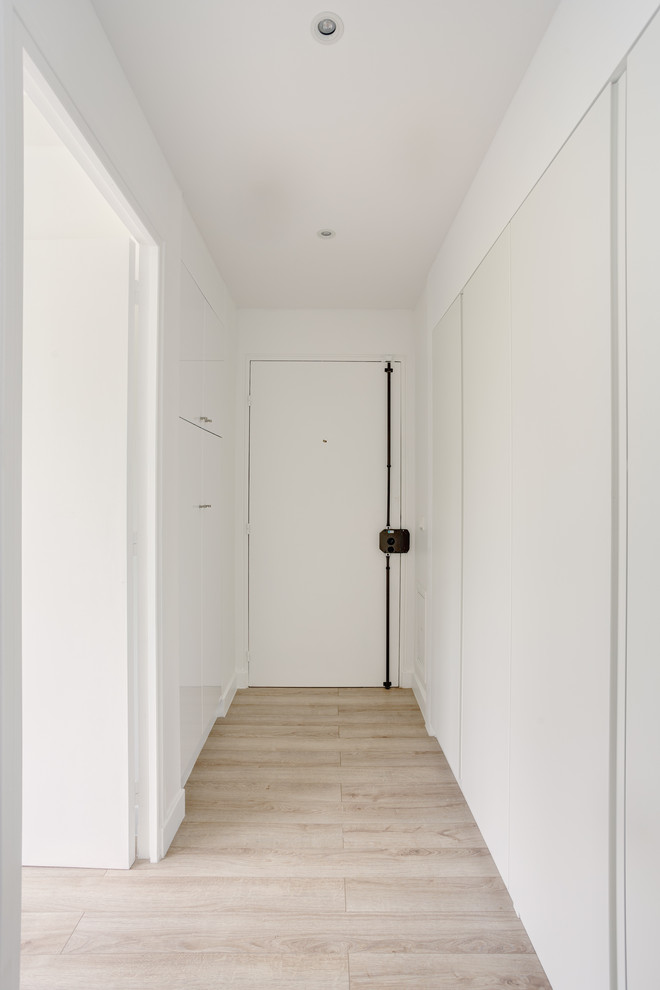 Imagen de hall nórdico pequeño con paredes blancas, suelo de madera clara, puerta simple, puerta blanca y suelo beige