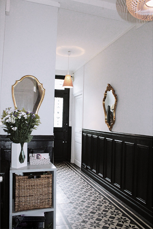 Retro Eingang mit Korridor, weißer Wandfarbe und schwarzer Haustür in Paris