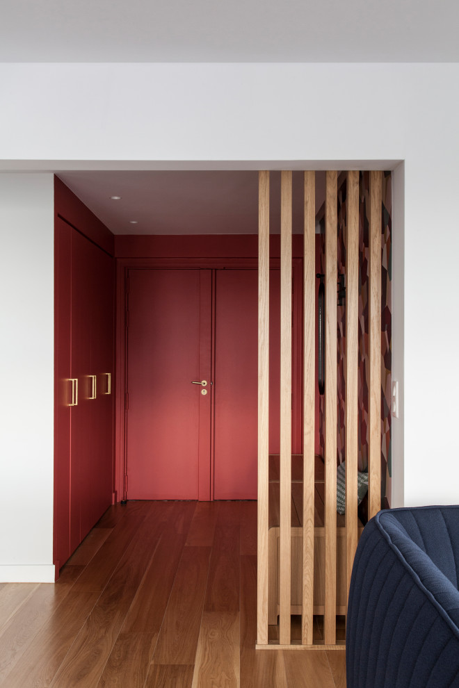 Foto på en mellanstor funkis foajé, med röda väggar, ljust trägolv, en dubbeldörr och en röd dörr