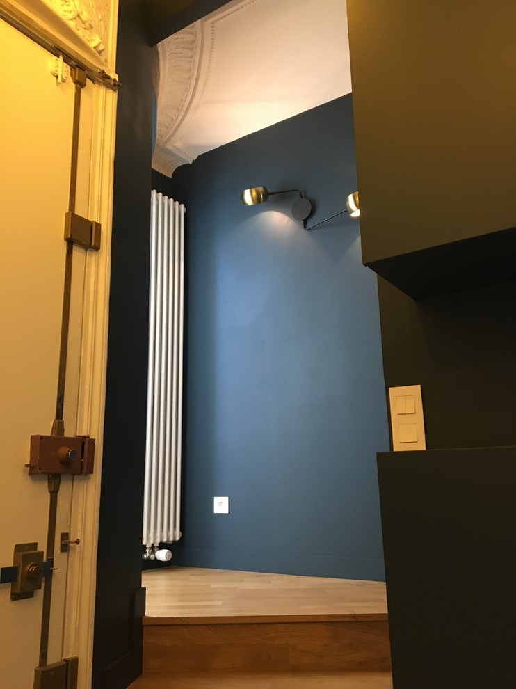 Aménagement d'un hall d'entrée contemporain de taille moyenne avec un mur bleu, parquet clair, une porte simple, une porte blanche et un sol beige.