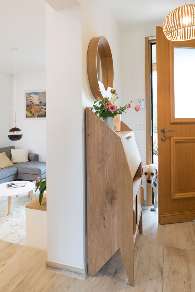 Kleines Modernes Foyer mit weißer Wandfarbe, hellem Holzboden, Einzeltür, hellbrauner Holzhaustür und beigem Boden in Paris