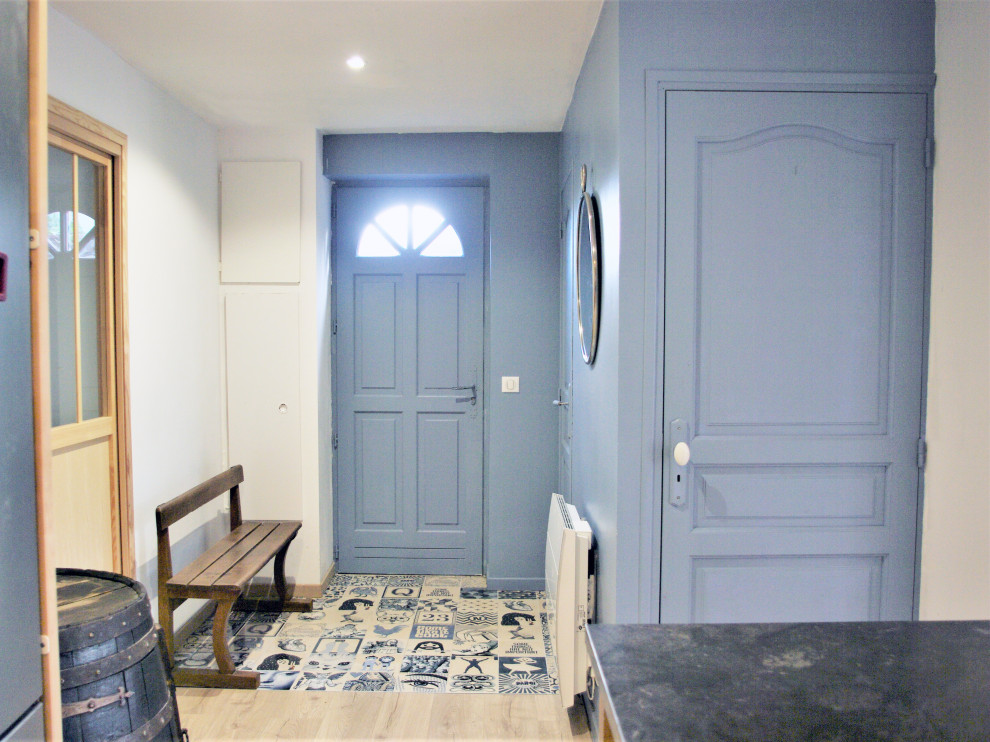 Bild på en liten lantlig hall, med blå väggar, laminatgolv, en blå dörr och beiget golv