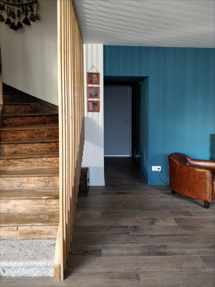 Große Landhaus Haustür mit blauer Wandfarbe, dunklem Holzboden und braunem Boden in Rennes