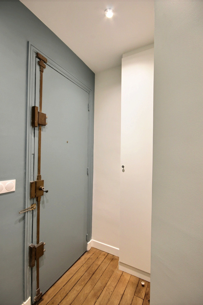 Foto di un piccolo corridoio chic con pareti blu, pavimento in legno massello medio, una porta singola e una porta blu