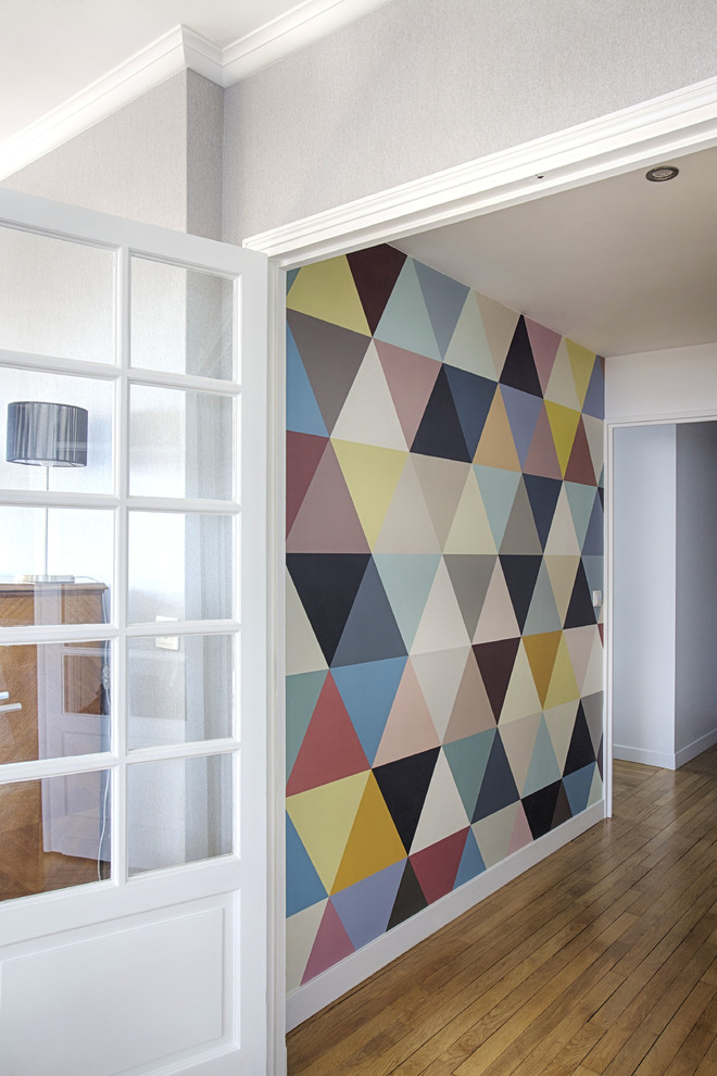 Réalisation d'une entrée minimaliste avec un mur multicolore et parquet clair.