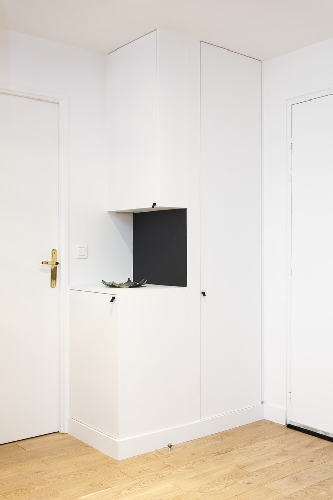 Modelo de vestíbulo escandinavo pequeño con paredes blancas, suelo de madera clara, puerta simple, puerta de madera en tonos medios y suelo marrón