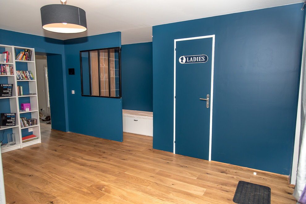 Immagine di un ingresso industriale con pareti blu, parquet chiaro, una porta singola e pavimento marrone