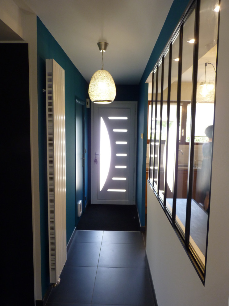 Réalisation d'une entrée design de taille moyenne avec un couloir, un mur bleu, un sol en carrelage de céramique, une porte simple, une porte blanche et un sol noir.