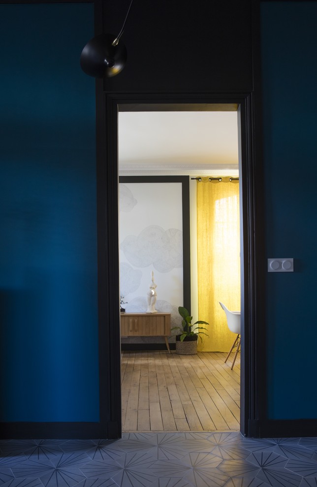 Idée de décoration pour un hall d'entrée bohème de taille moyenne avec un mur bleu, sol en béton ciré et un sol gris.
