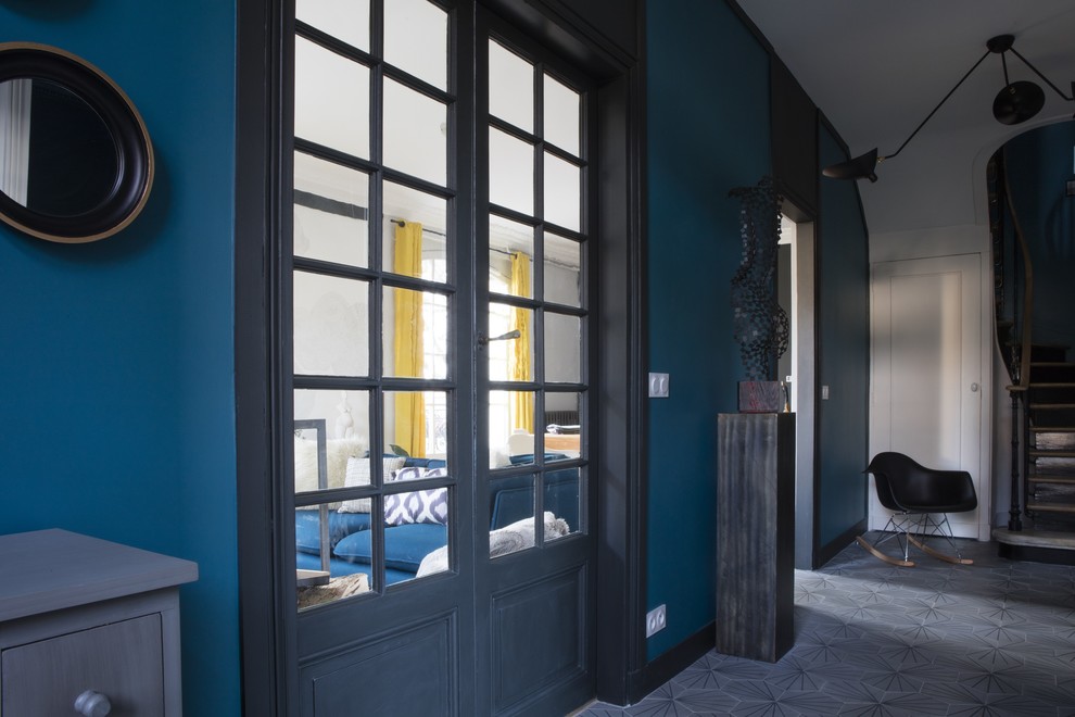 Idée de décoration pour un hall d'entrée bohème de taille moyenne avec un mur bleu, sol en béton ciré et un sol gris.