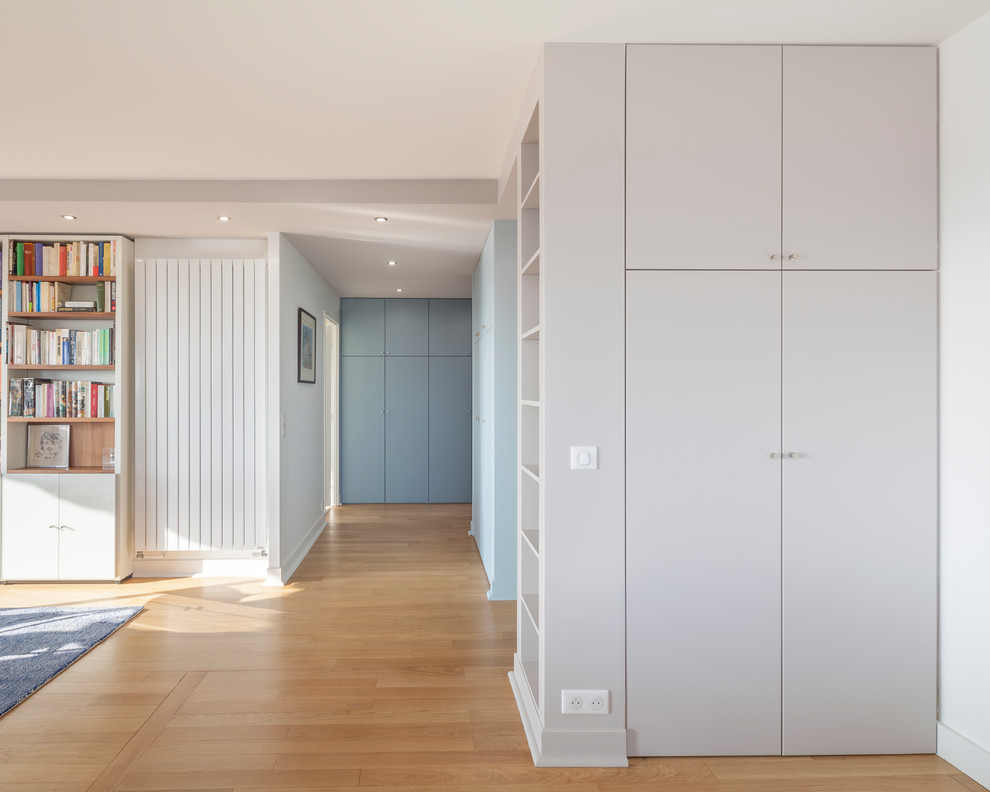 Diseño de distribuidor actual grande con paredes multicolor, suelo de madera clara, puerta simple y puerta azul