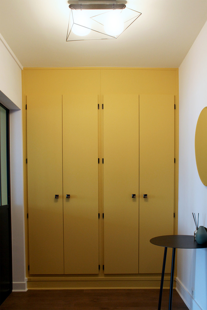 パリにあるコンテンポラリースタイルのおしゃれな玄関ラウンジ (黄色い壁、無垢フローリング、濃色木目調のドア) の写真