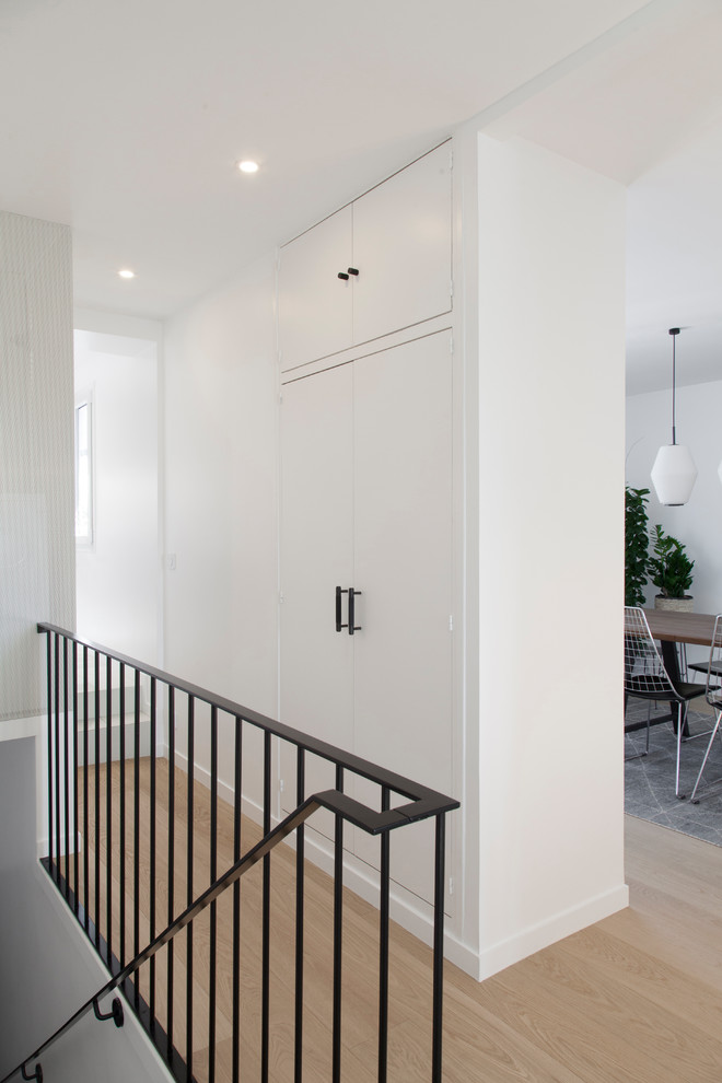 Idées déco pour un couloir contemporain de taille moyenne avec un mur blanc, parquet clair et un sol beige.