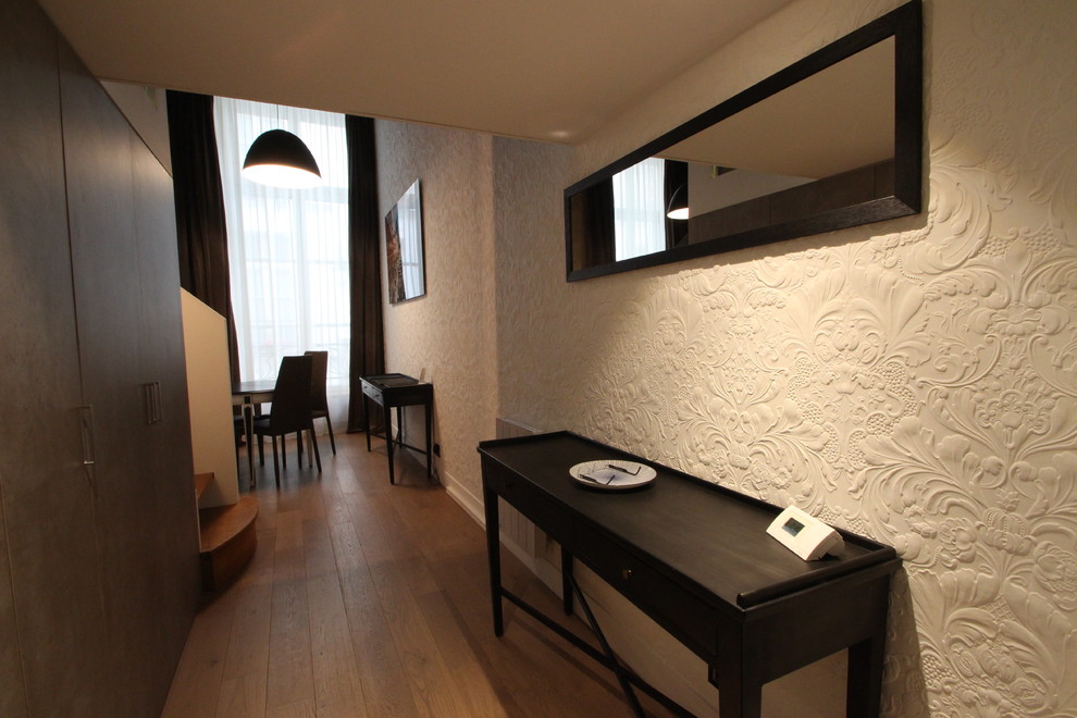 Cette photo montre une entrée tendance de taille moyenne avec un couloir, un mur beige et un sol en bois brun.
