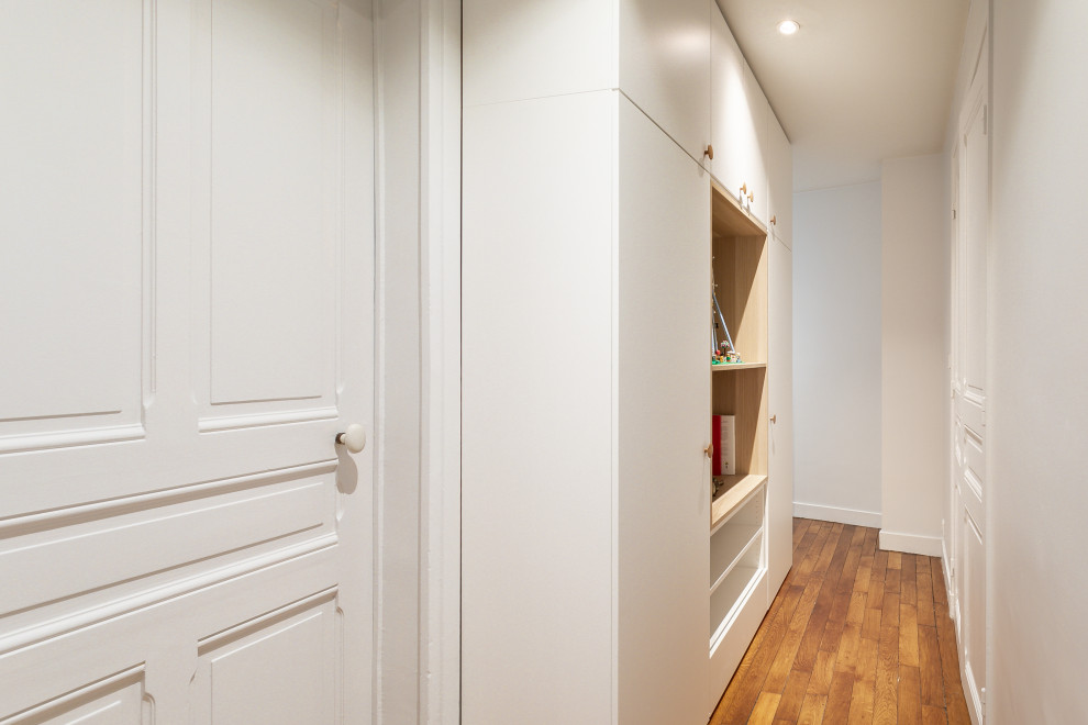 Idées déco pour une entrée contemporaine de taille moyenne avec un couloir, un mur blanc, parquet clair, une porte blanche et un sol marron.