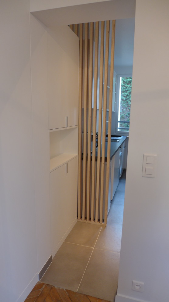 Immagine di un piccolo corridoio scandinavo con pareti bianche, pavimento con piastrelle in ceramica, una porta singola e pavimento grigio