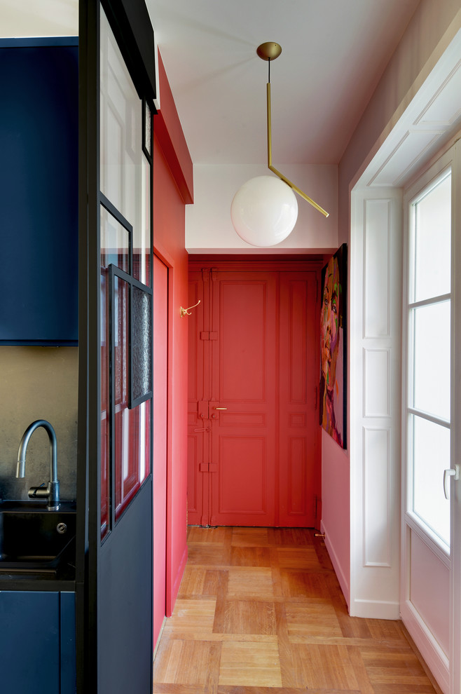 Ejemplo de hall tradicional renovado pequeño con paredes rojas, suelo de madera clara y puerta roja