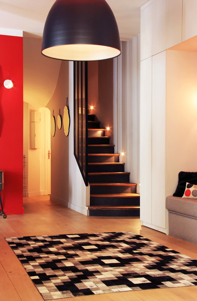 This is an example of a medium sized contemporary foyer in Paris with red walls and light hardwood flooring.