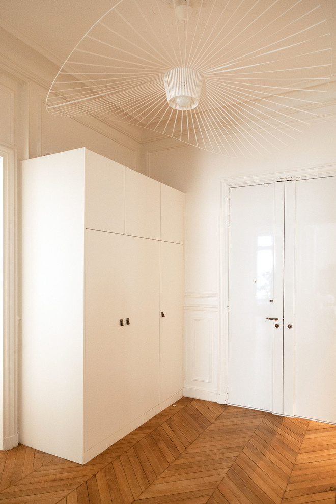 Réalisation d'un hall d'entrée design de taille moyenne avec un mur blanc, un sol en bois brun, un sol marron, une porte double et une porte blanche.