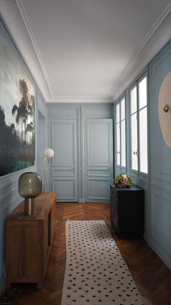 Foto de hall contemporáneo grande con paredes azules, suelo de madera en tonos medios, puerta simple, puerta azul y suelo marrón