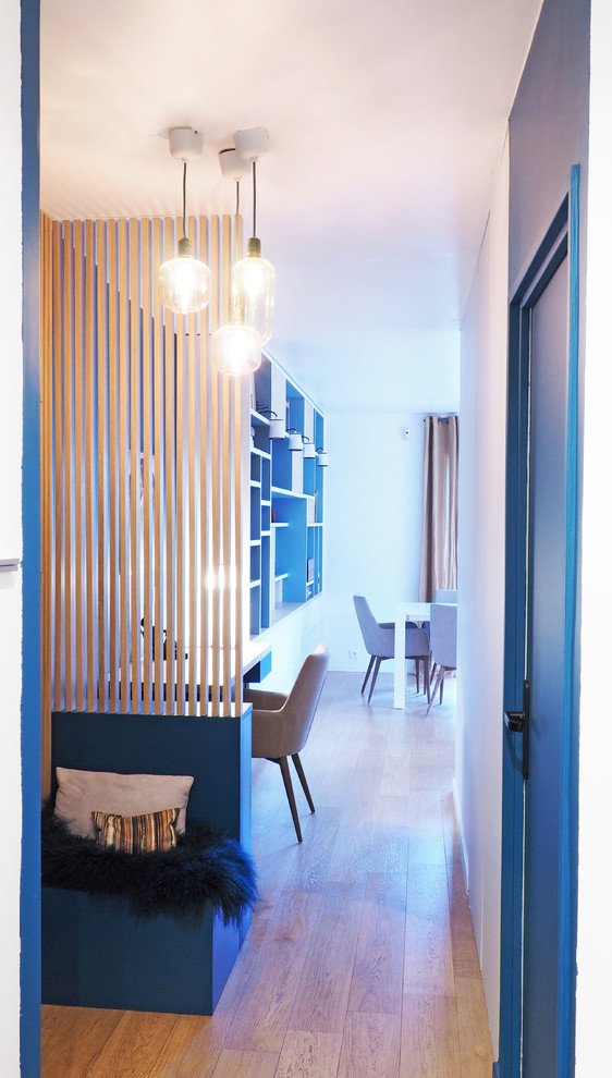 Réalisation d'une porte d'entrée design de taille moyenne avec un mur bleu, parquet clair, une porte simple, une porte bleue et un sol marron.