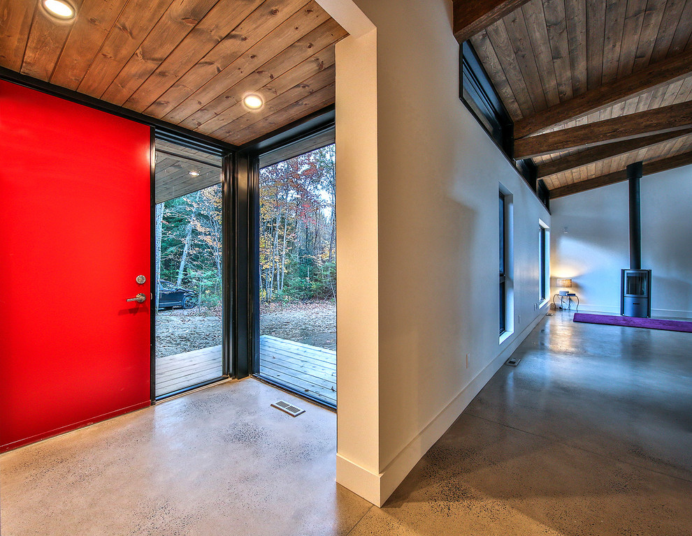 モントリオールにある小さなコンテンポラリースタイルのおしゃれな玄関ロビー (白い壁、コンクリートの床、赤いドア) の写真