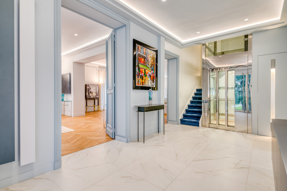Réalisation d'un très grand hall d'entrée minimaliste avec un mur bleu, un sol en carrelage de céramique, une porte simple, une porte métallisée et un sol blanc.