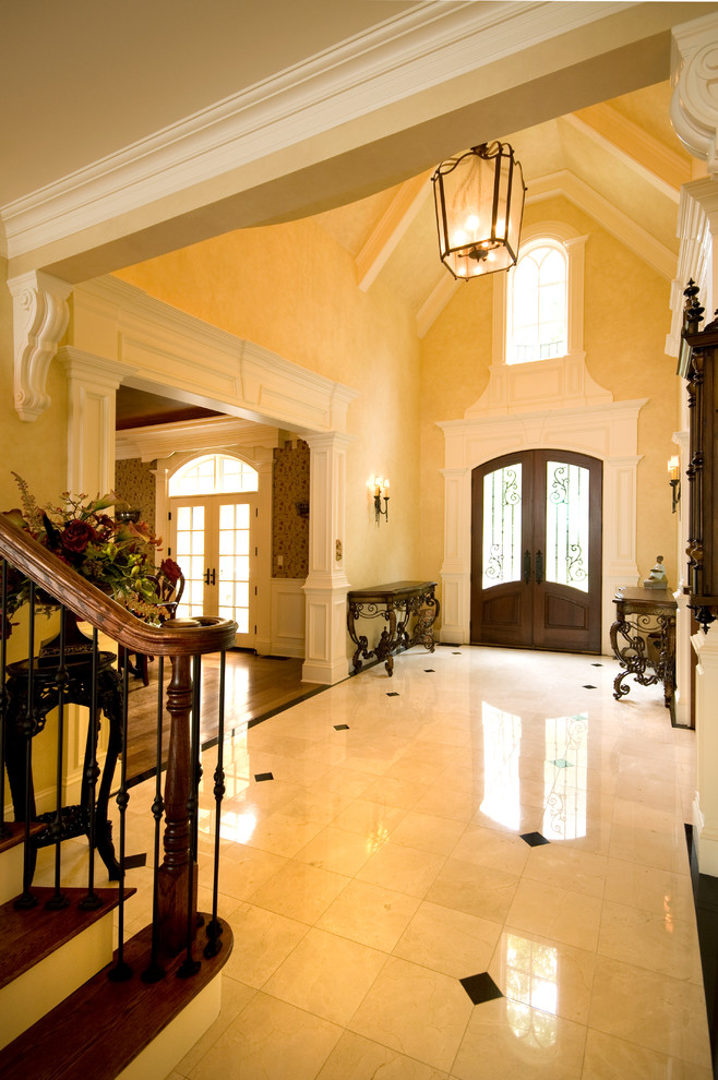 Inspiration pour un grand hall d'entrée traditionnel avec un mur beige, un sol en carrelage de porcelaine, une porte double, une porte en bois foncé et un sol beige.