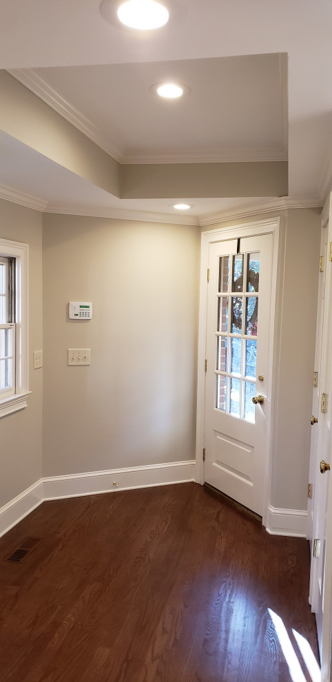 Foto på ett mellanstort vintage kapprum, med grå väggar, mellanmörkt trägolv, en enkeldörr, en vit dörr och brunt golv