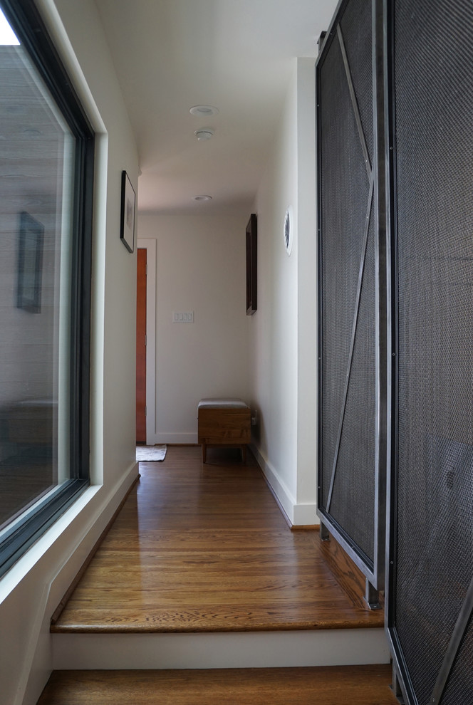 Esempio di un ingresso con anticamera moderno di medie dimensioni con pareti bianche, pavimento marrone, parquet scuro, una porta a due ante e una porta in vetro