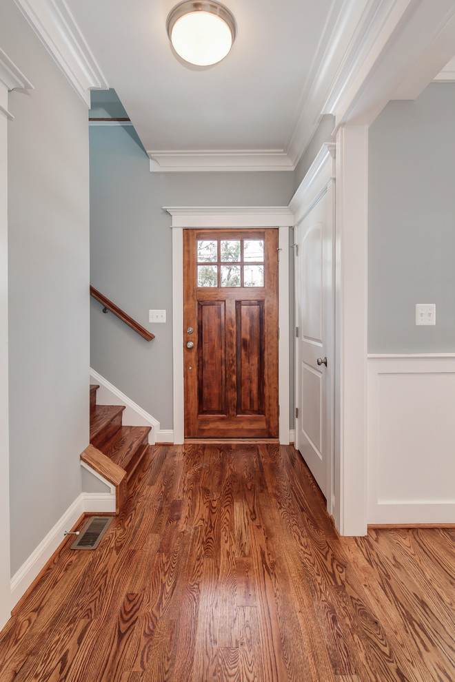 Immagine di una porta d'ingresso chic con pareti grigie, pavimento in legno massello medio, una porta singola e una porta in legno bruno