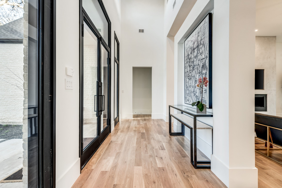 Entryway - large contemporary light wood floor and white floor entryway idea in Dallas with white walls and a black front door