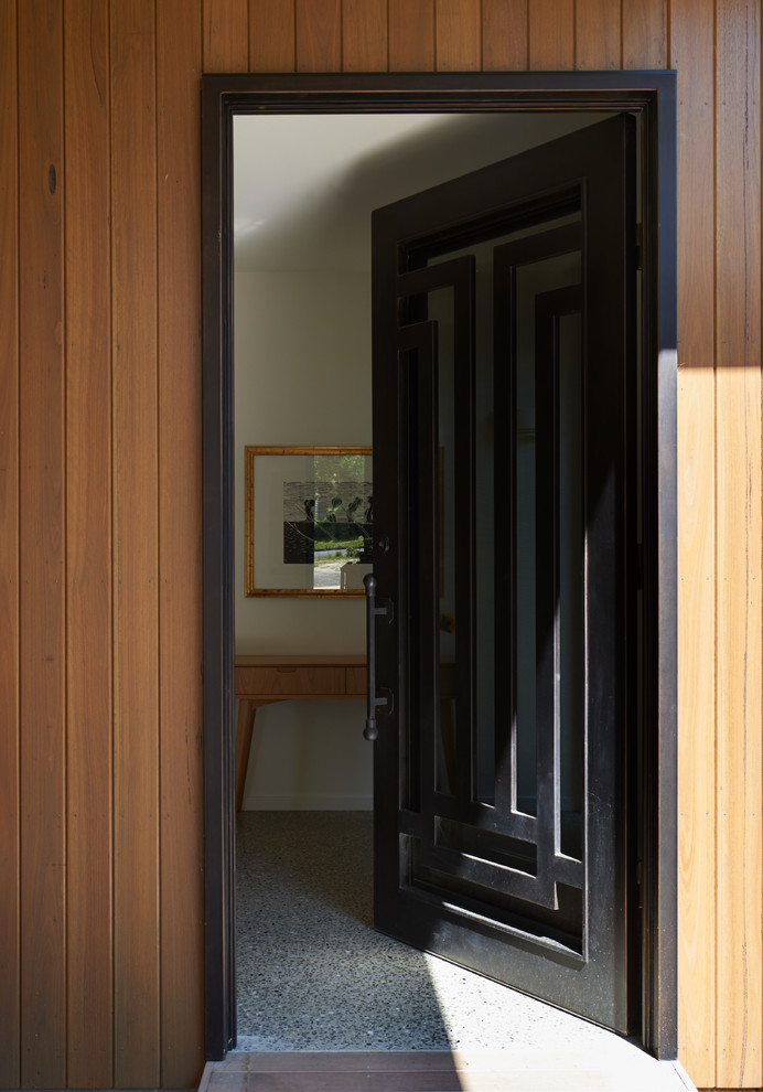 Cette photo montre une petite porte d'entrée tendance avec sol en béton ciré, une porte simple et une porte noire.