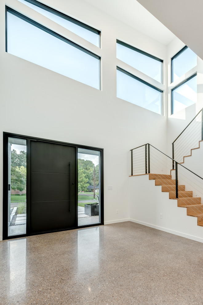 Источник вдохновения для домашнего уюта: входная дверь в стиле модернизм с серыми стенами, бетонным полом, поворотной входной дверью, черной входной дверью, серым полом и кирпичными стенами