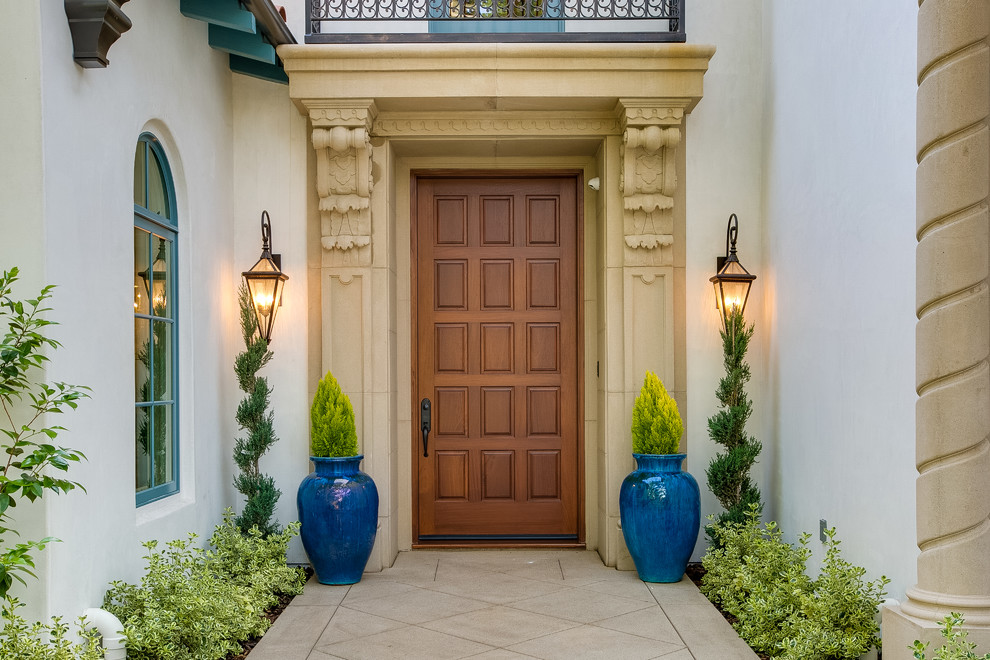 This is an example of a mediterranean front door in Los Angeles with white walls, a single front door and a medium wood front door.