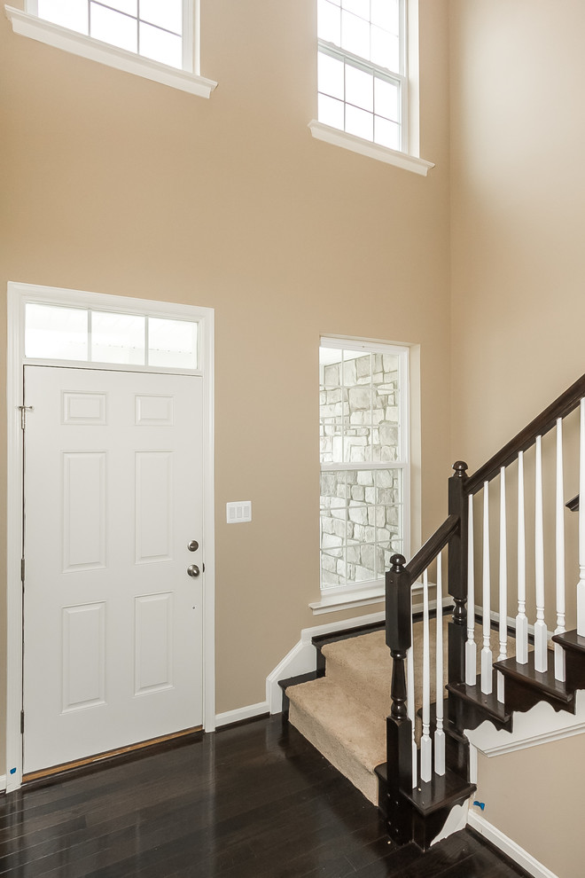 Exemple d'un grand hall d'entrée chic avec un mur beige, parquet foncé, une porte simple et une porte blanche.