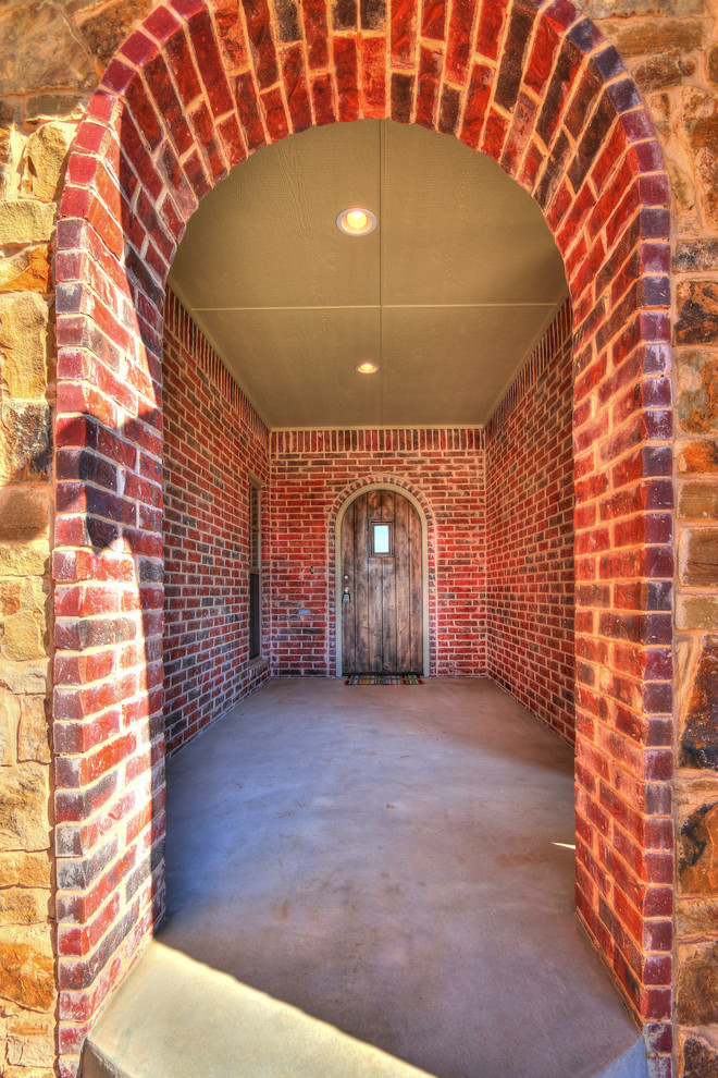 Стильный дизайн: входная дверь среднего размера в стиле рустика с красными стенами, бетонным полом, одностворчатой входной дверью, входной дверью из дерева среднего тона и серым полом - последний тренд
