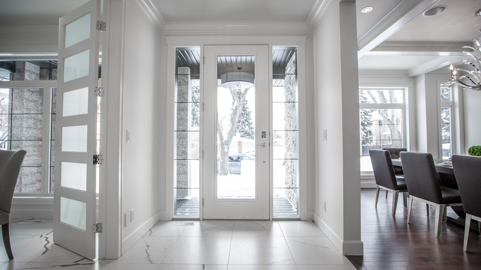 На фото: большое фойе в стиле неоклассика (современная классика) с белыми стенами, темным паркетным полом, одностворчатой входной дверью и белой входной дверью с
