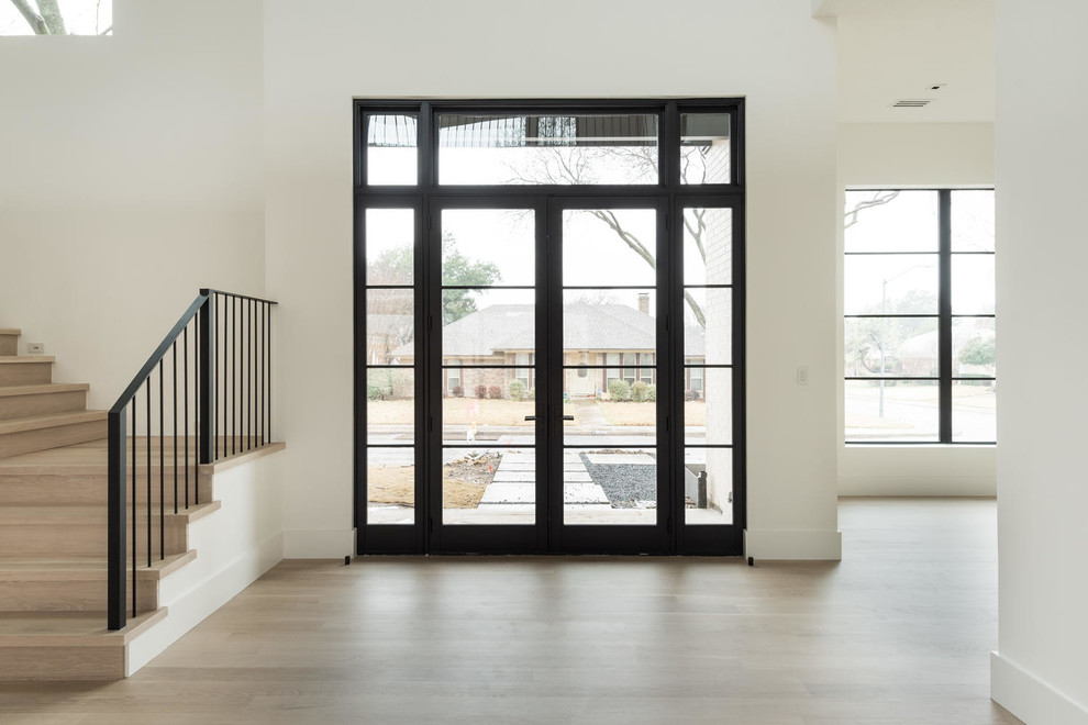 На фото: входная дверь среднего размера в стиле модернизм с белыми стенами, светлым паркетным полом, двустворчатой входной дверью, черной входной дверью и коричневым полом