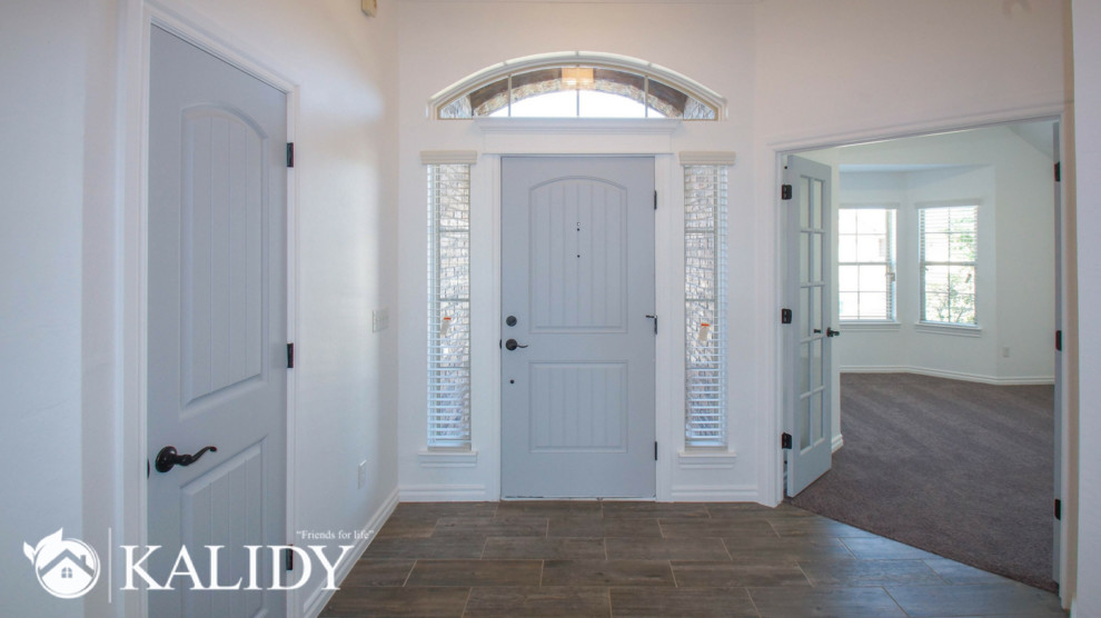 Foto di un grande ingresso tradizionale con pareti bianche, pavimento con piastrelle in ceramica, una porta singola, una porta grigia e pavimento marrone