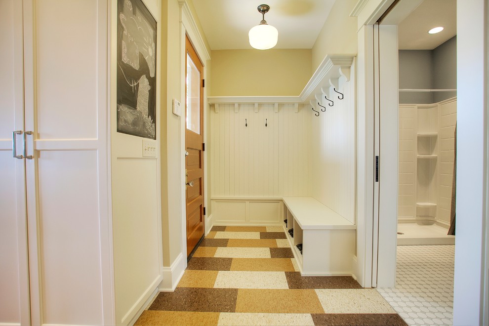 Idées déco pour une entrée craftsman avec un vestiaire, un mur jaune, un sol en linoléum et une porte en bois brun.